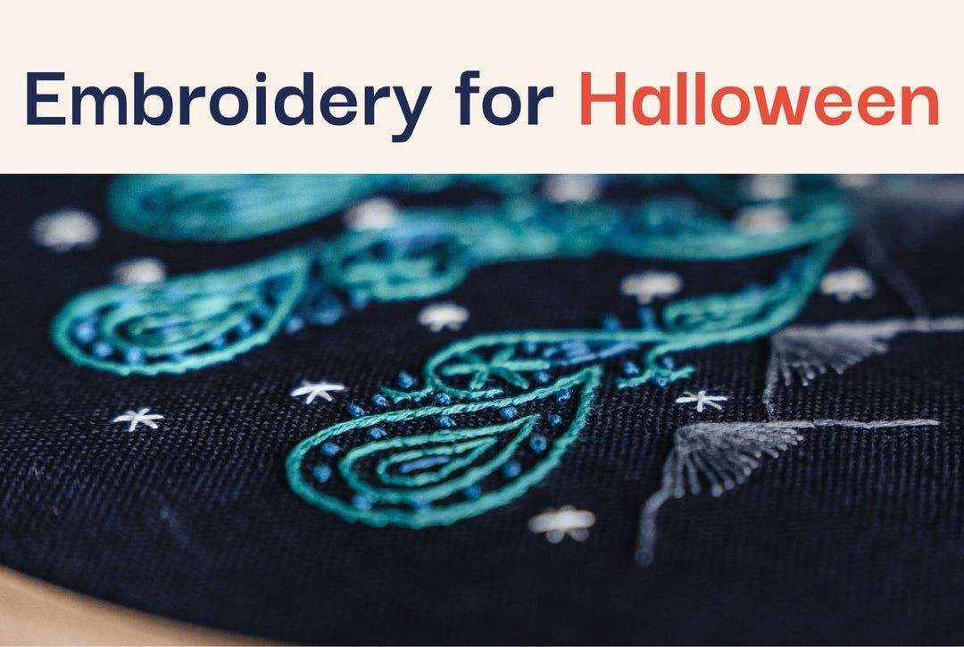 A close up photo of an embroidered northern lights design on navy fabric.