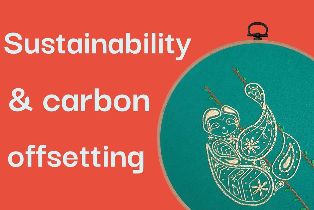 An embroidery hoop holding green fabric stitched with a smiling sloth design.