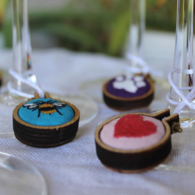Three prosecco charms including bee heart and pawprint on blue pink and purple fabric