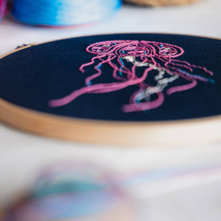 An angled closeup of the tail end of a finished jellyfish embroidery design on navy fabric. Made using this jellyfish embroidery kit product.