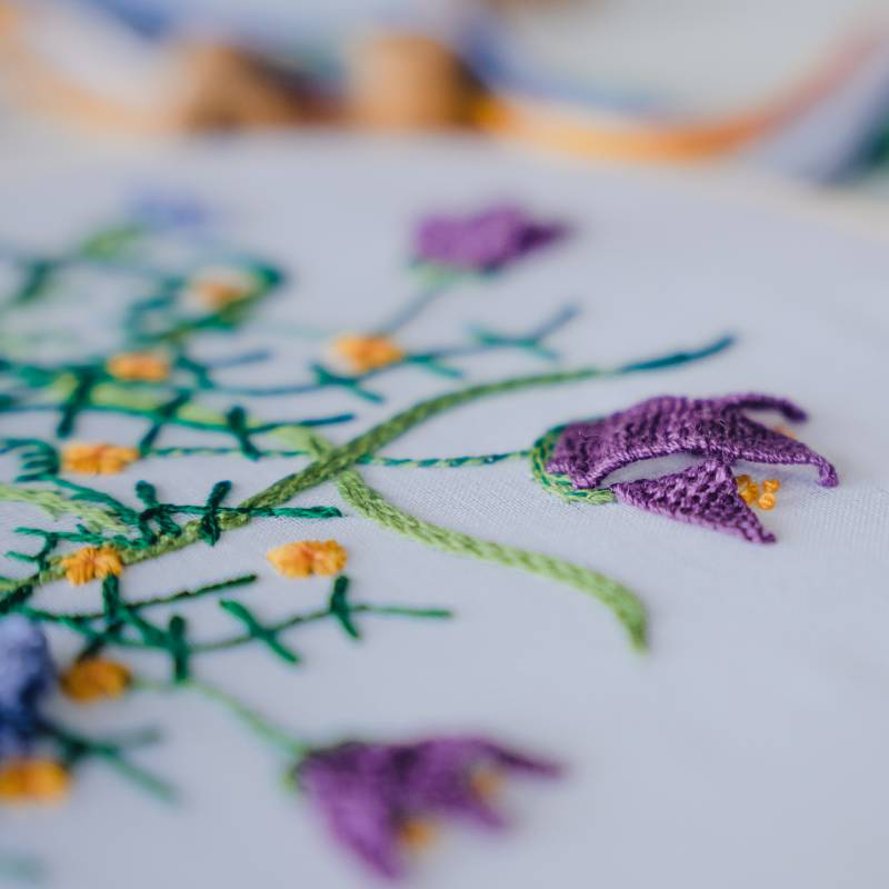 A close up of William Morris inspired floral embroidery on white voile fabric..