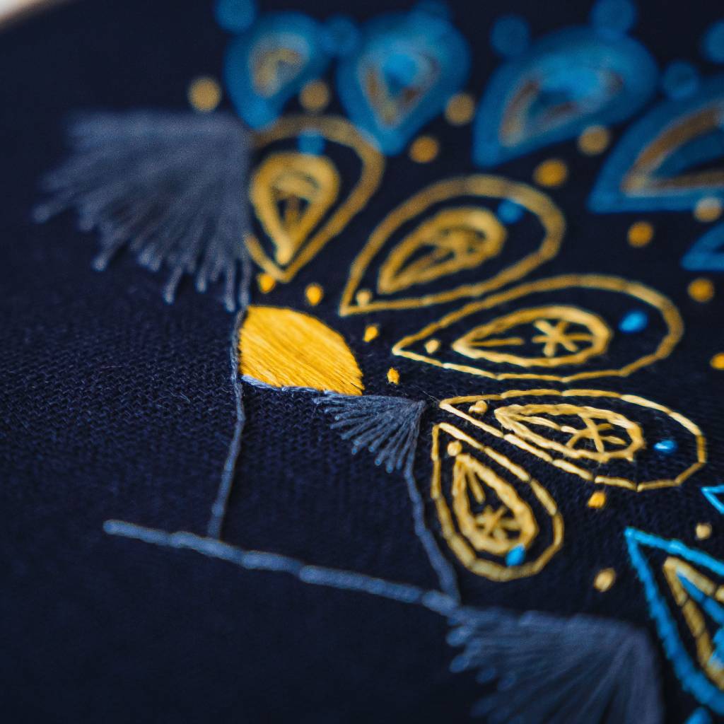 A close up angled photo from the centre of a sunrise embroidery design on navy fabric. Made using this sunrise embroidery kit product.