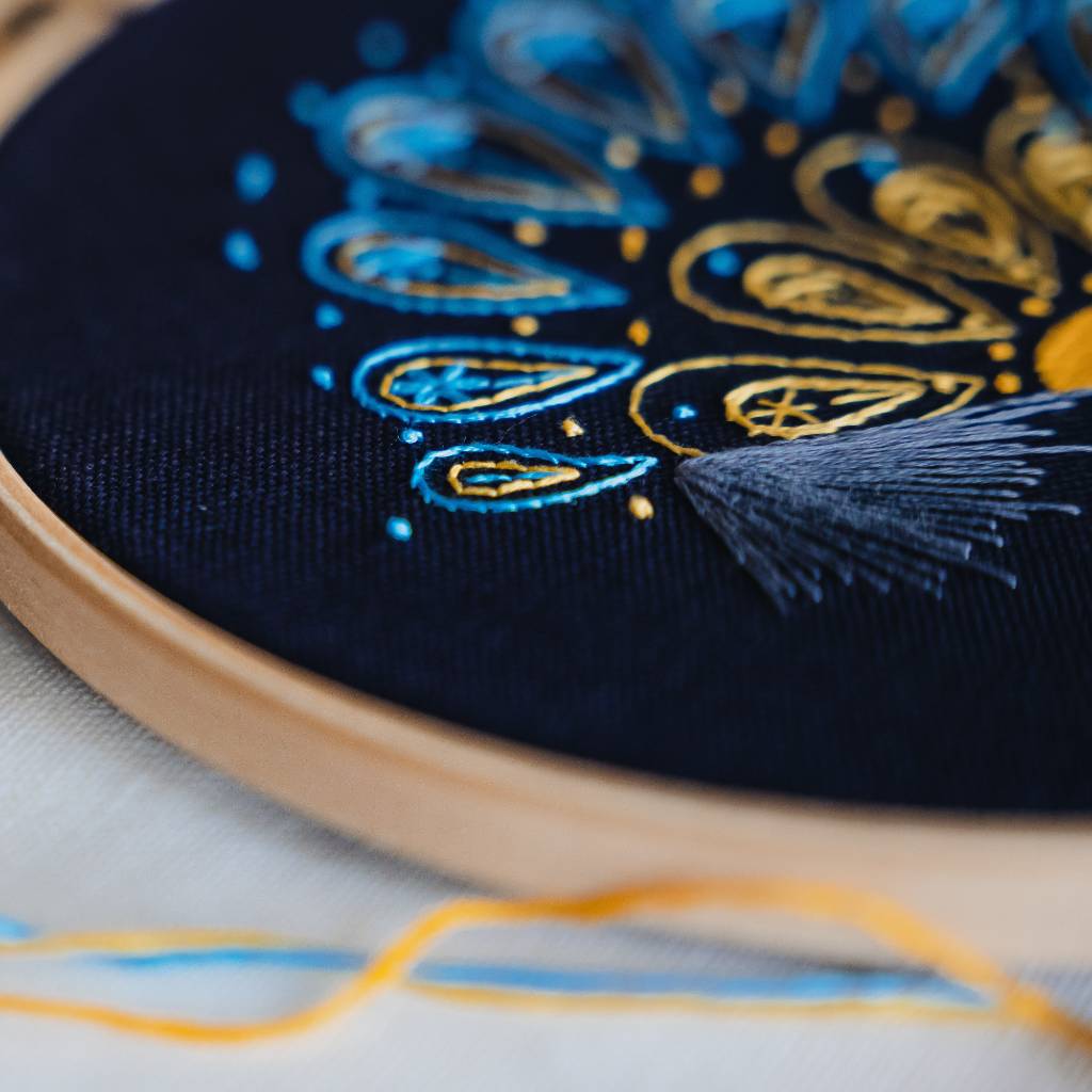 A close up angled photo from the left of a sunrise embroidery design on navy fabric. Made using this sunrise embroidery kit product.