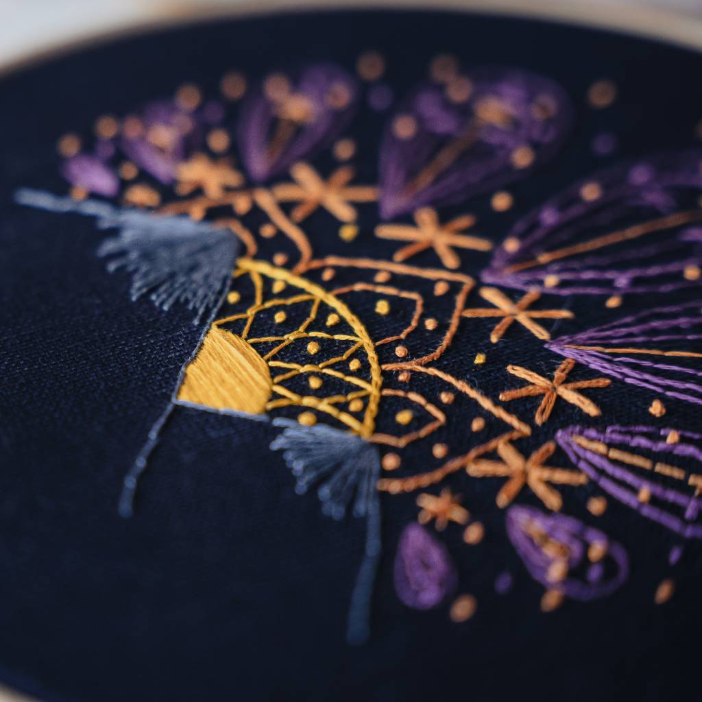 An angled closeup of a sunset embroidery design on navy fabric. Made using this sunset embroidery kit product.