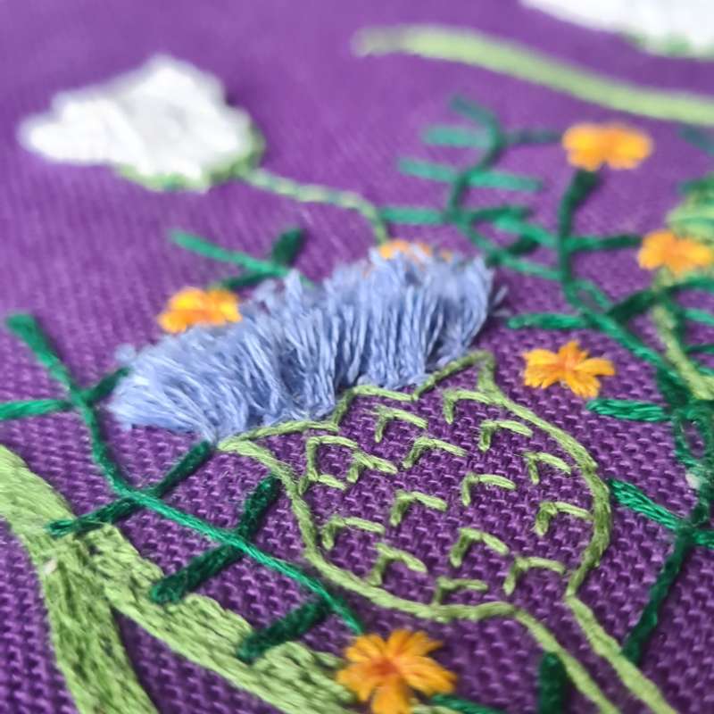 thistle embroidered on purple fabric