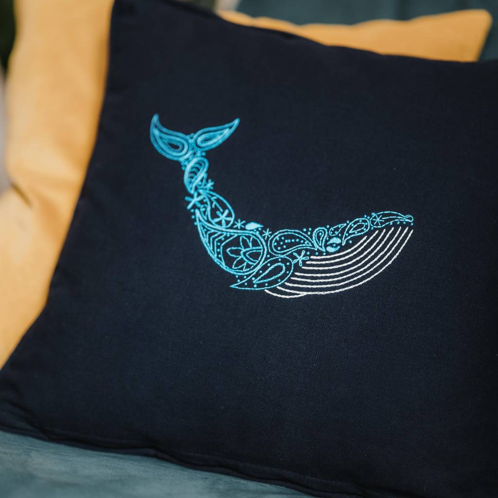 A finished whale embroidery design on an organic navy cushion, made using a whale cushion embroidery kit product.