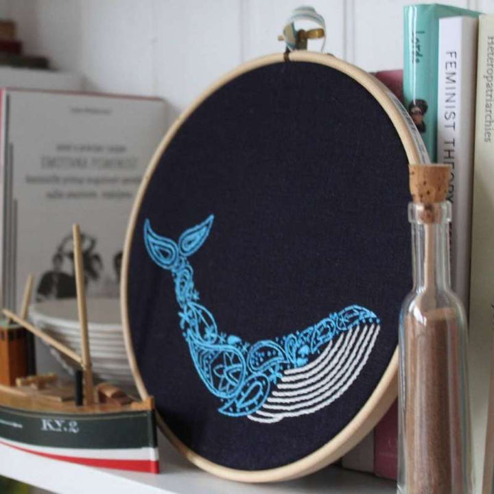 Paisley whale angled photo showing the whale embroidery kit completed and resting on a shelf with ornaments