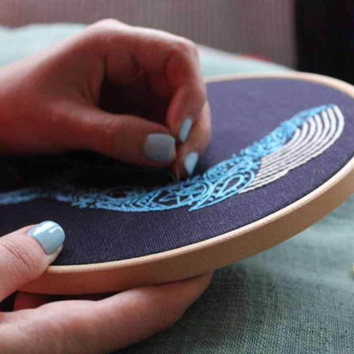 Paisley whale embroidery design being stitched on navy blue fabric 