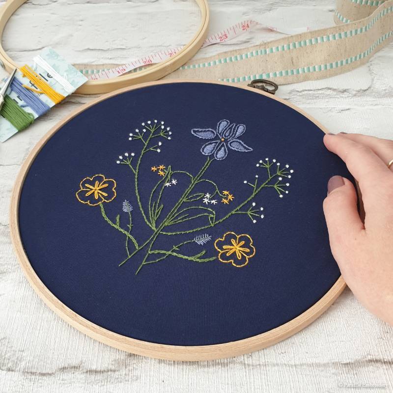 Detail view of paisley botanical embroidery on navy fabric in wooden hoop