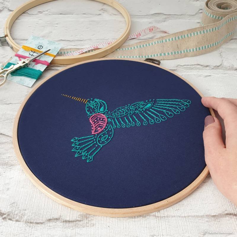 Detail view of paisley hummingbird hand embroidery on navy fabric