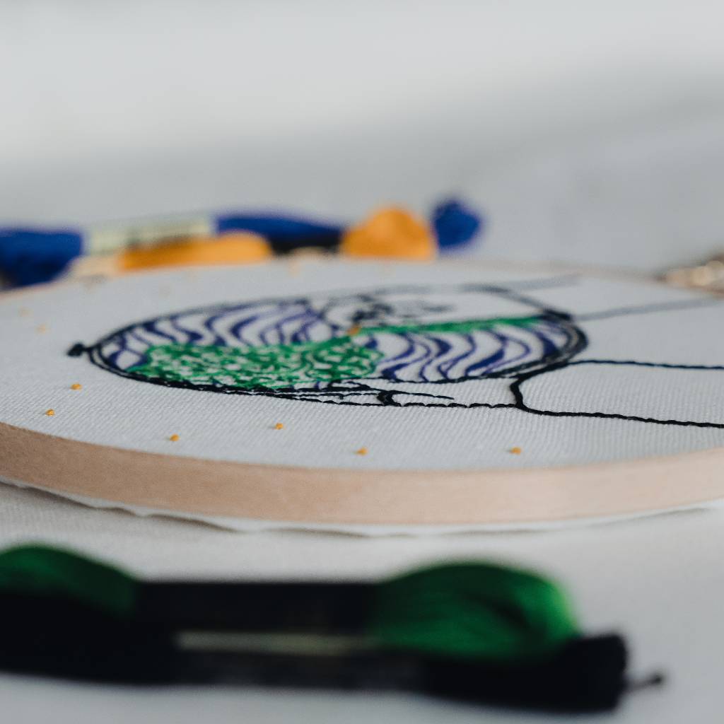 Side view of an embroidery hoop, with embroidery thread in the foreground and background.