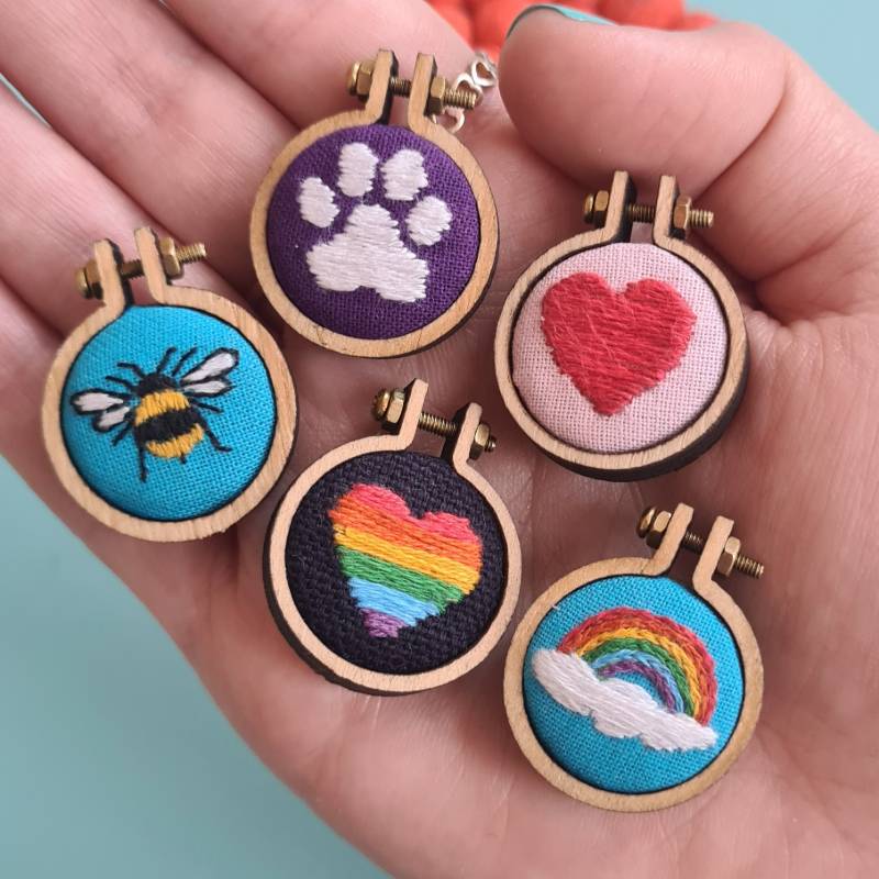 five different embroidery charms in a hand
