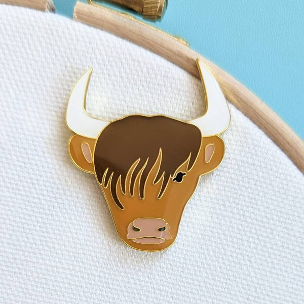 A close up of a Highland Cow magnetic design on a white fabric background.