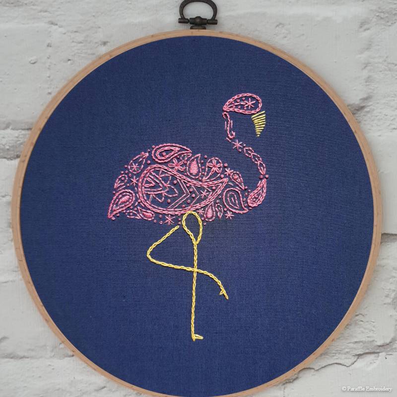 Detail view of paisley flamingo embroidery on navy fabric