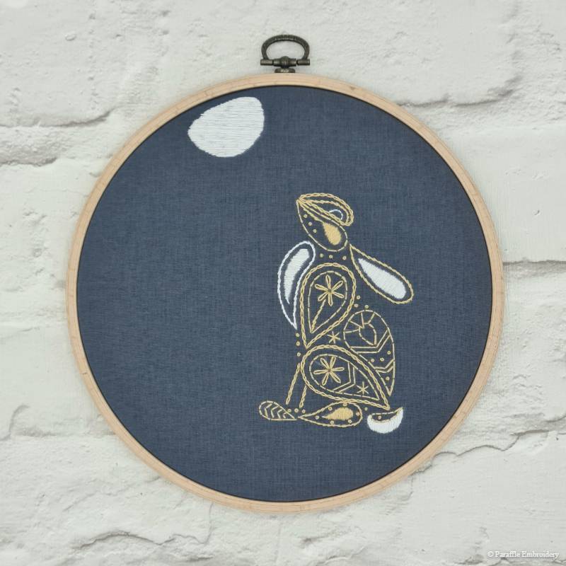 Detail picture of hare embroidery on grey fabric in wooden hoop